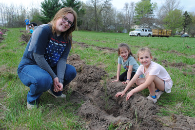Kindergarten students planting trees with a high school student